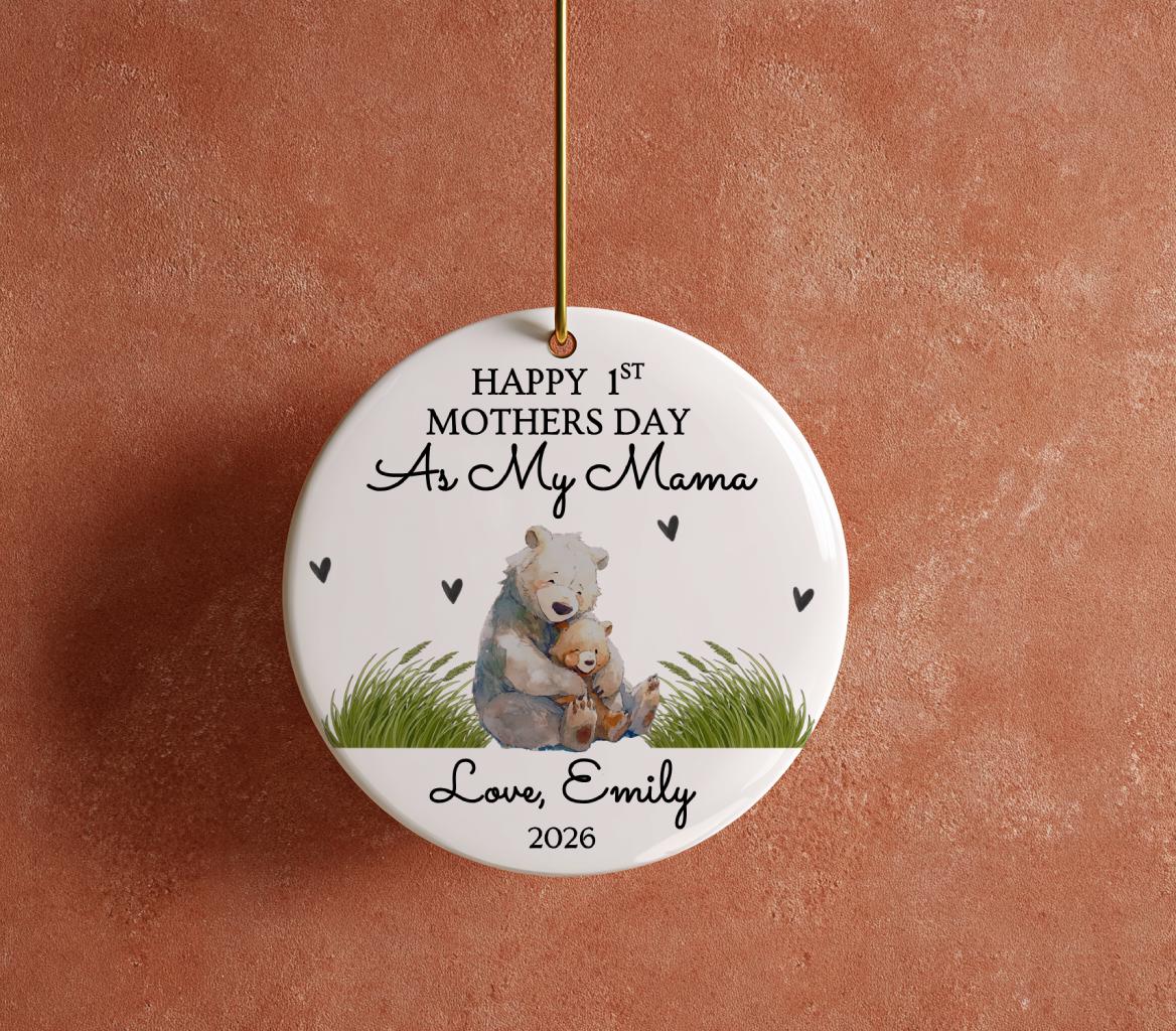 May include: A white ceramic ornament with a gold string for hanging. The ornament features a watercolor illustration of a bear hugging a cub, with the text "Happy 1st Mothers Day As My Mama Love, Emily 2026".