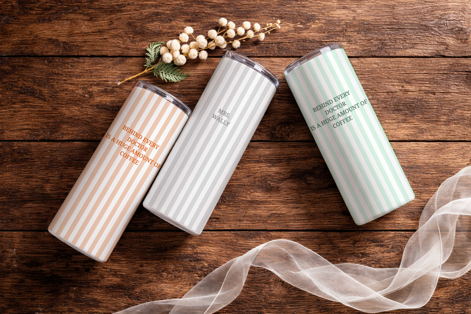 Three personalized tumblers on a wooden surface with decorative elements.