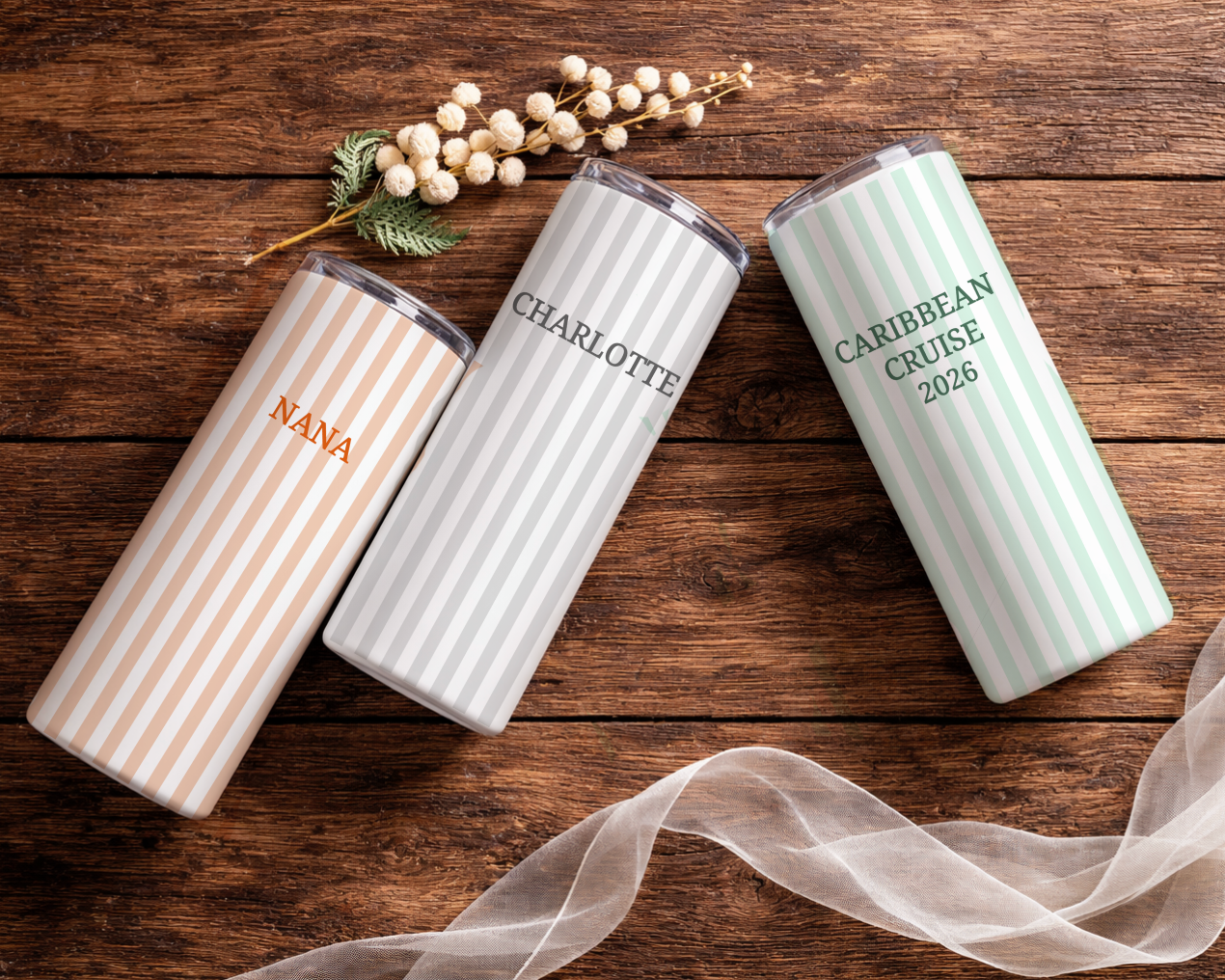 Three personalized tumblers on a wooden surface with decorative elements.
