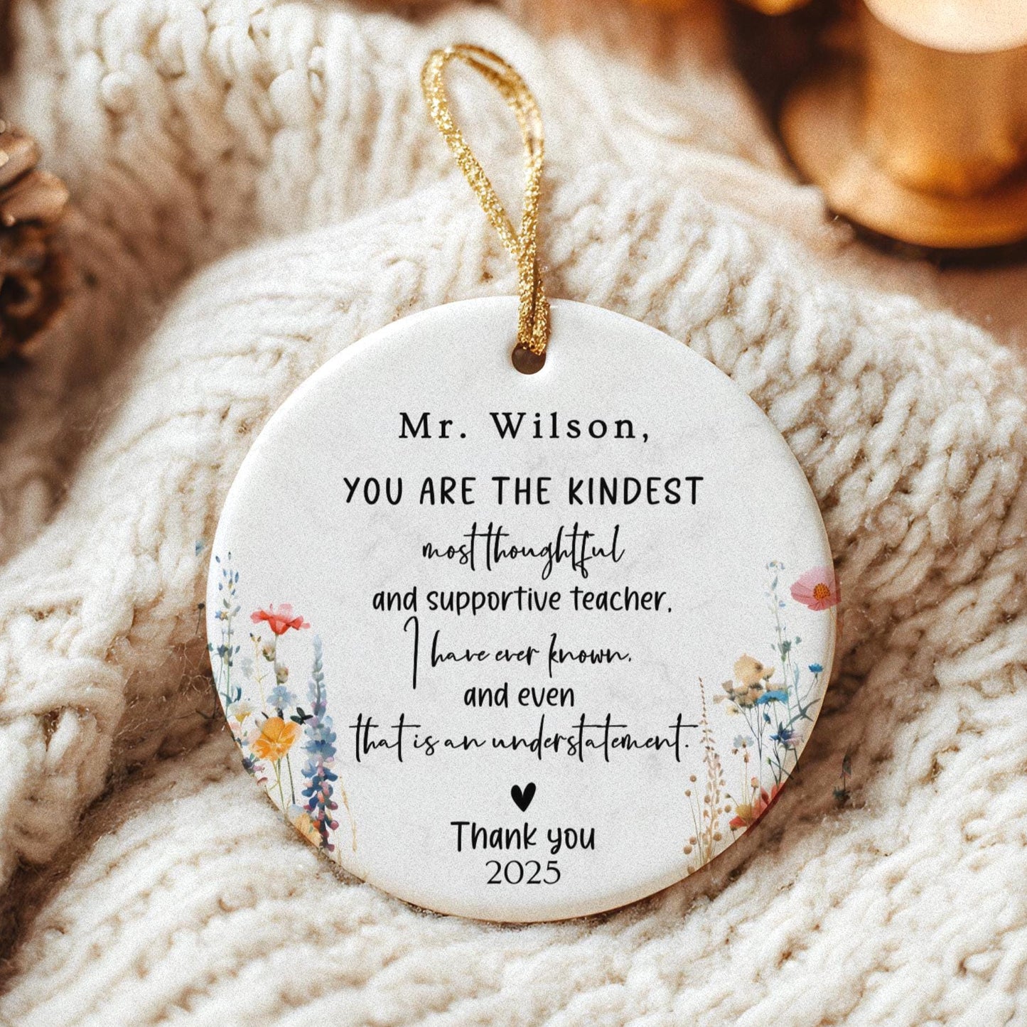 May include: A white ceramic ornament with a gold string for hanging. The ornament features floral designs and text that reads, 'Mr. Wilson, YOU ARE THE KINDEST most thoughtful and supportive teacher. I have ever known and even that is an understatement. Thank you 2025.'