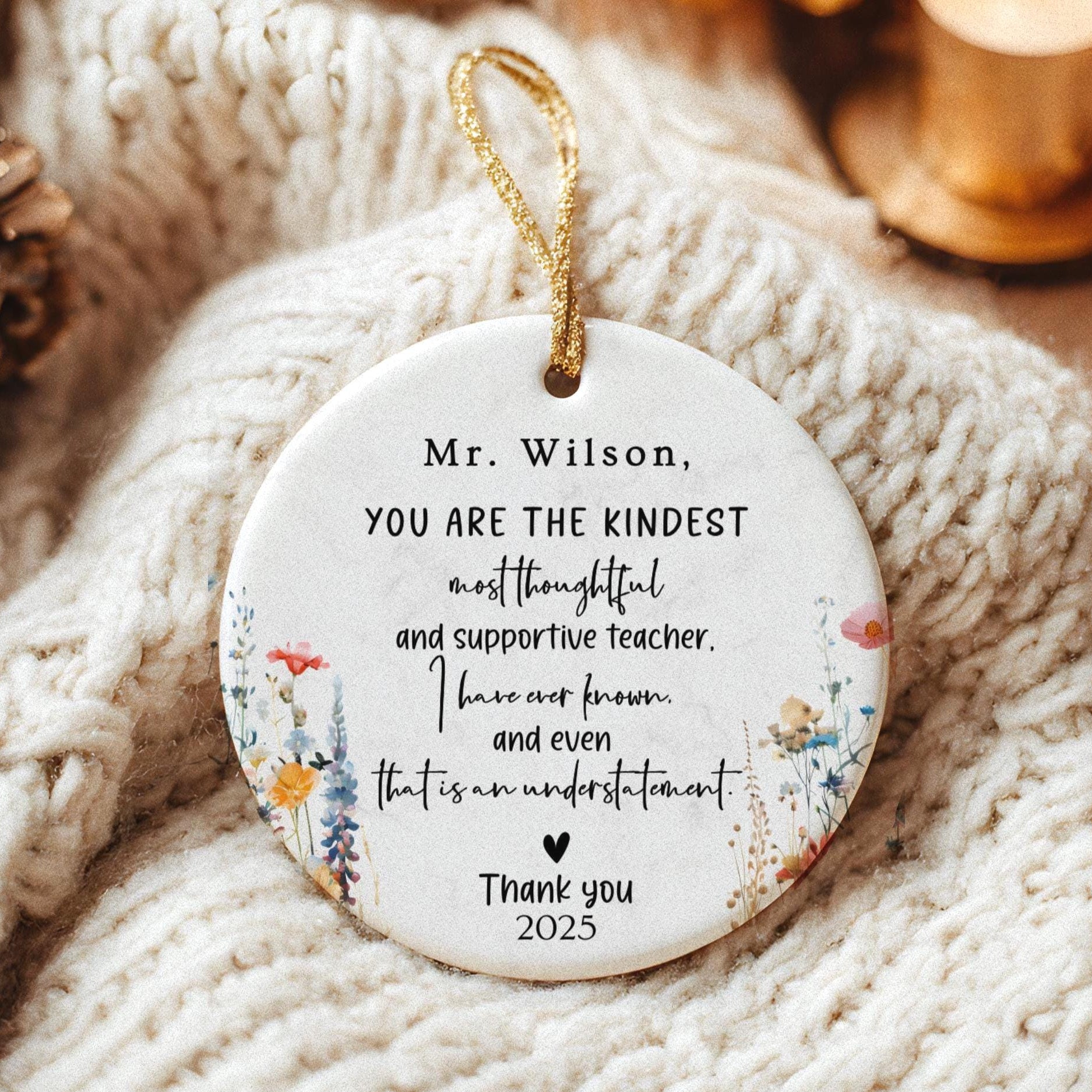 May include: A white ceramic ornament with a gold string for hanging. The ornament features floral designs and text that reads, 'Mr. Wilson, YOU ARE THE KINDEST most thoughtful and supportive teacher. I have ever known and even that is an understatement. Thank you 2025.'