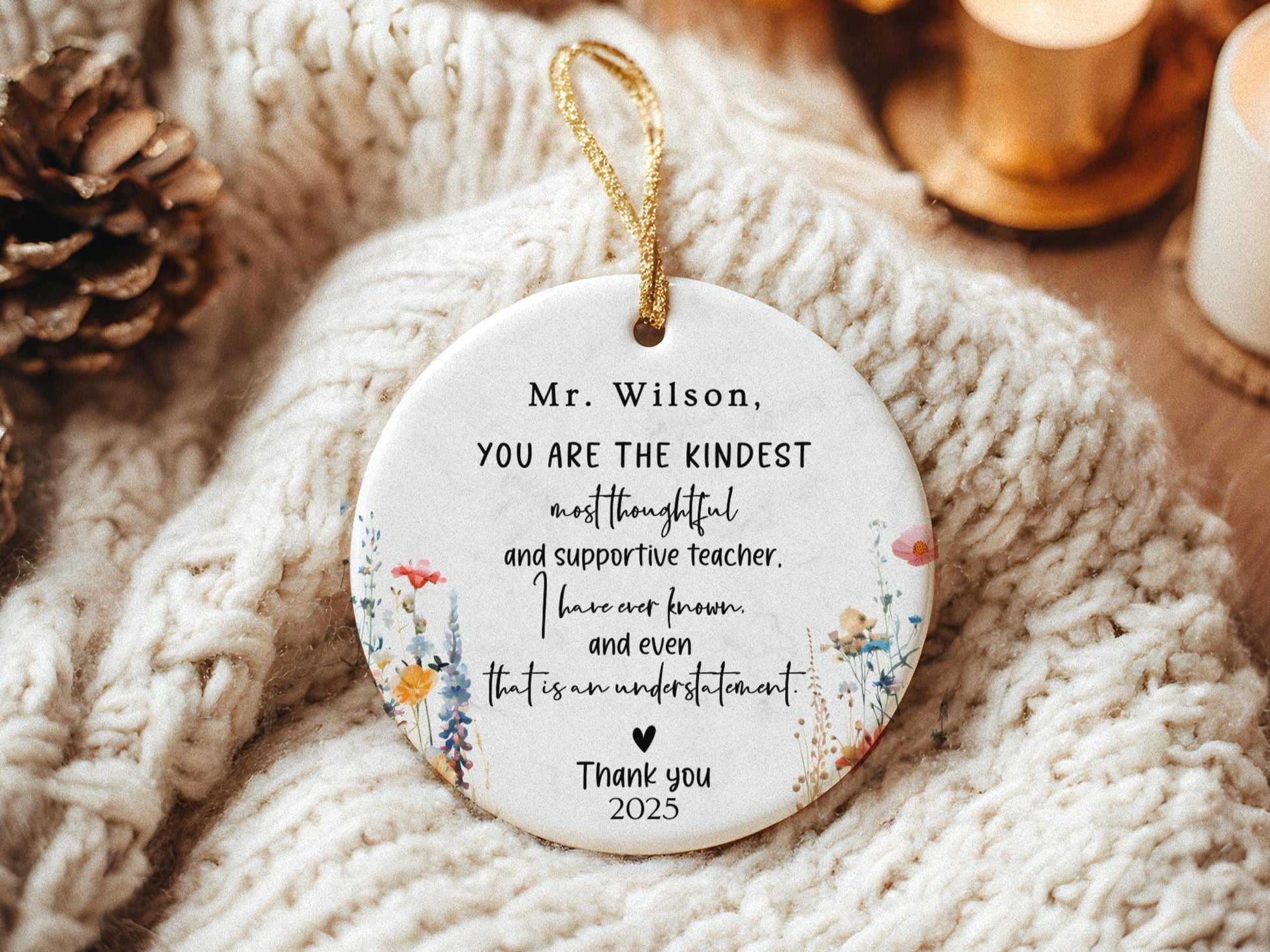 May include: A white ceramic ornament with a gold string for hanging. The ornament features floral designs and text that reads, &#39;Mr. Wilson, YOU ARE THE KINDEST most thoughtful and supportive teacher. I have ever known and even that is an understatement. Thank you 2025.&#39;