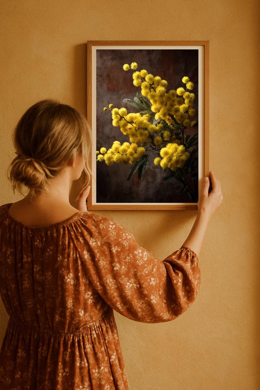 Woman holding golden mimosa flower rustic art print, warm brown dress, cozy vintage interior wall art.