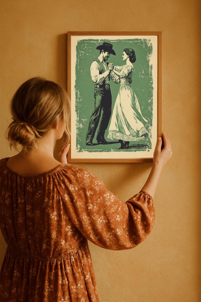 A retro style cowboy with a hat and a cowgirl in a lace dress are dancing on a vintage green, distressed background. The wall art is in the antique bronze frame. The lady is facing to right side and hanging the wall art on a terracota colored wall.