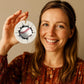 Baseball mom proudly is holding Custom baseball ornament featuring 3D cracked effect and editable player name.
