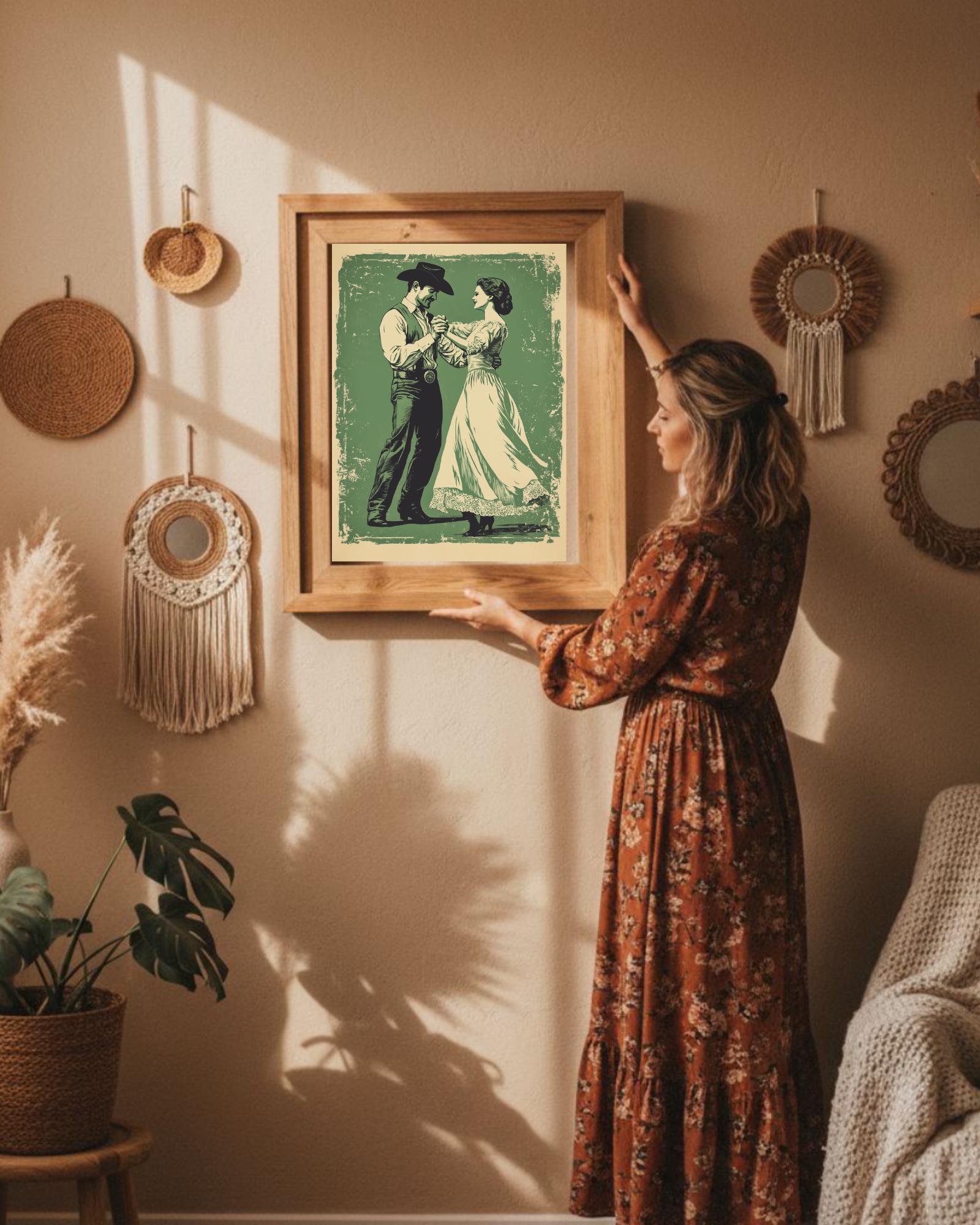A retro style cowboy with a hat and a cowgirl in a lace dress are dancing on a vintage green, distressed background. The wall art is in the antique bronze frame. The lady is facing to left side hanging the wall art on a beige color wall. decorated with bohemian look wall decors such as macrame designs.