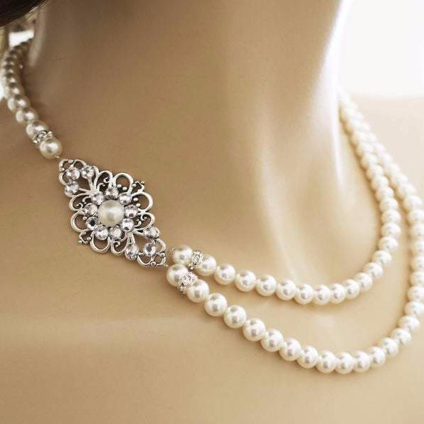 Vintage-style Art Deco bridal necklace with an elegant side-set crystal brooch and double strands of classic pearls, perfect for wedding day glamour.